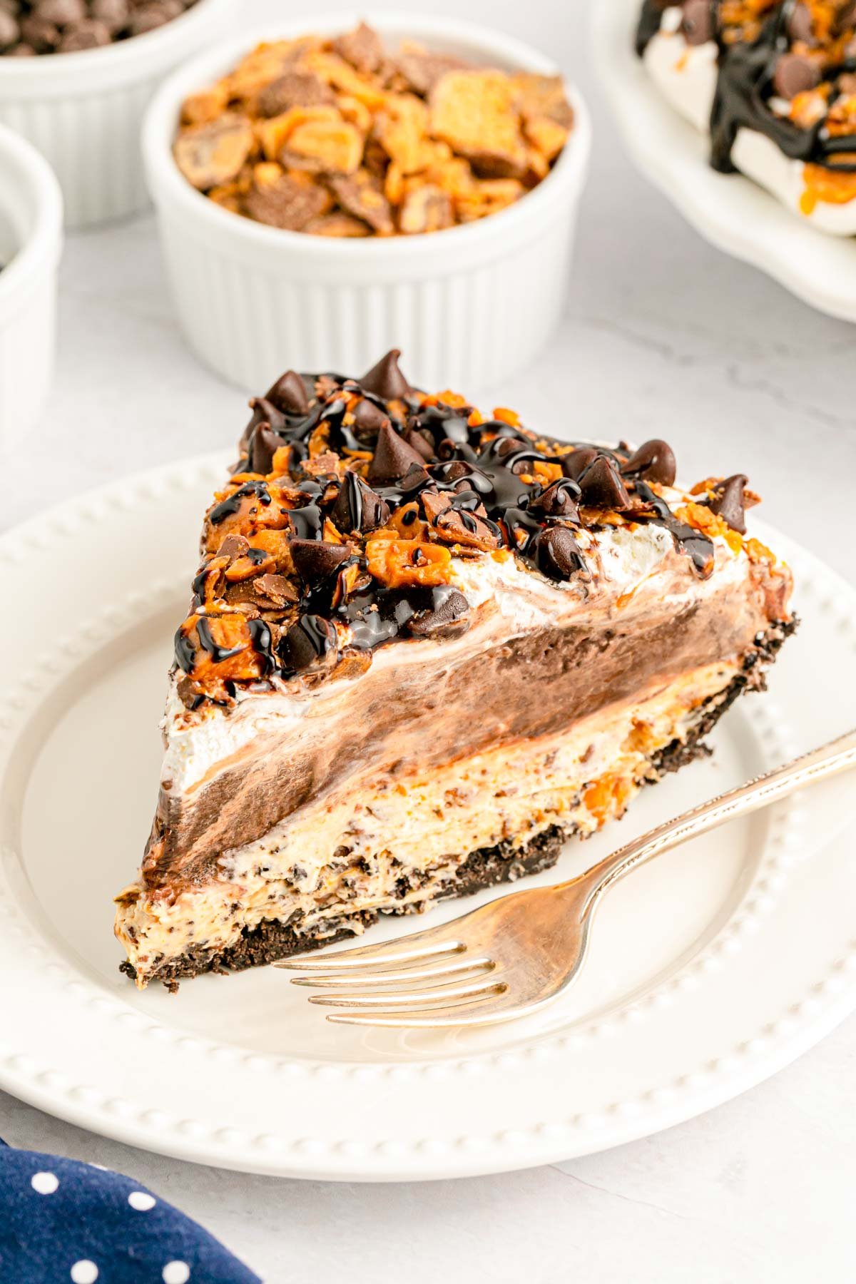 A close up of a slice of no bake butterfinger pie on a white plate.