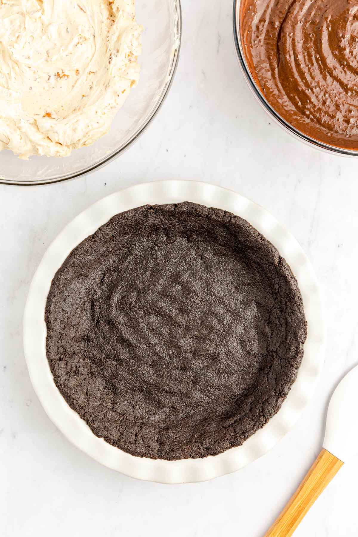 Oreo crust in a white pie dish.