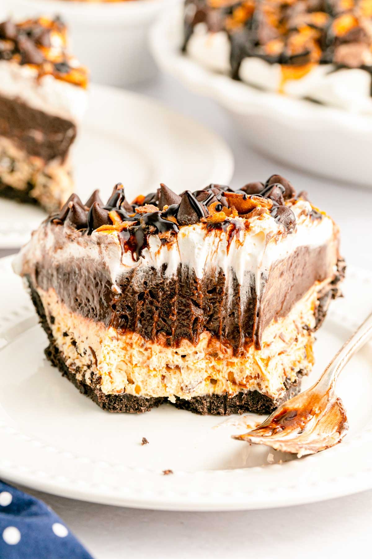 A  slice of butterfinger pie on a white plate with bites missing out of it.