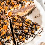 Overhead photo of a butterfinger no bake pie in a white pie dish with a slice missing.