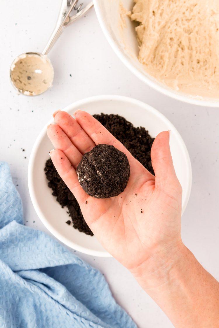 Oreo coated cookie dough ball in a woman's hand.