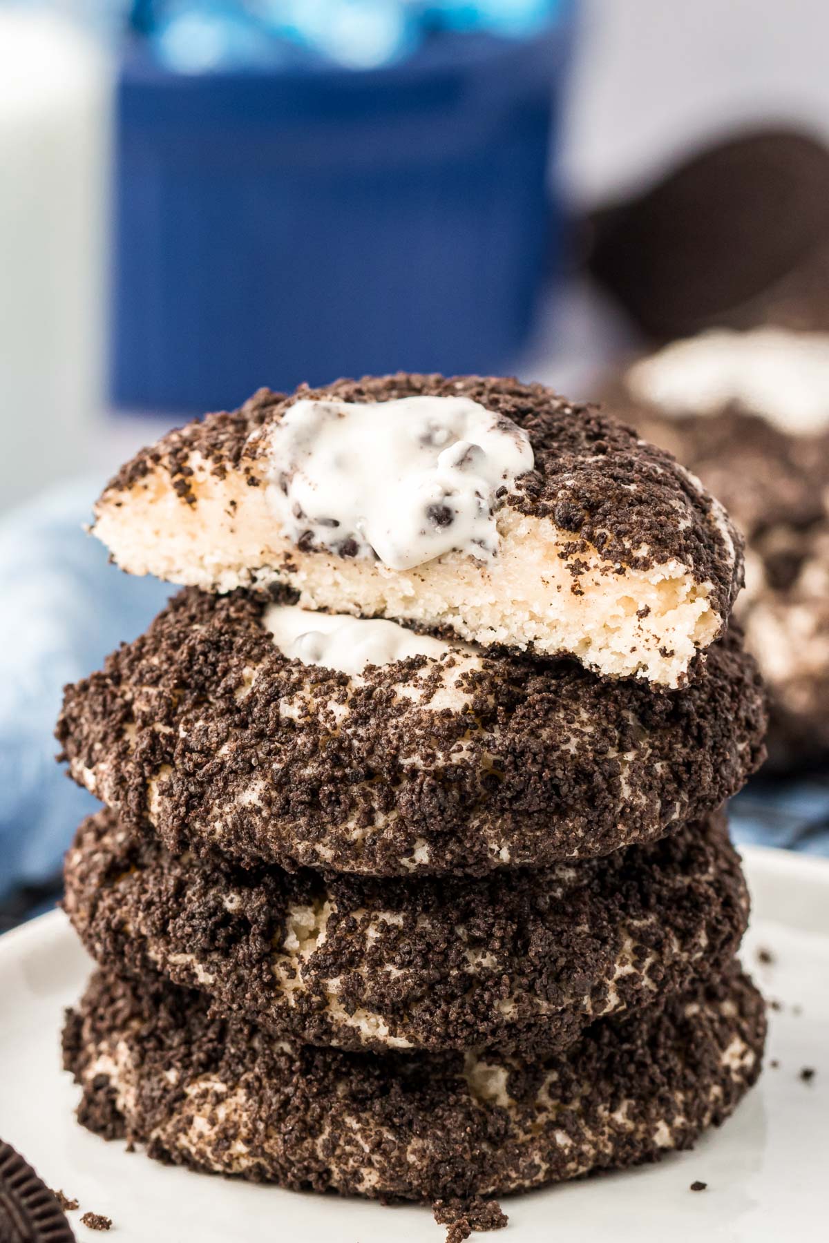 A stack of four Oreo thumbprint cookies on a white plate, the top one has been cut in half.