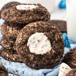 A stack of Oreo thumbprint cookies with one leaning against it.