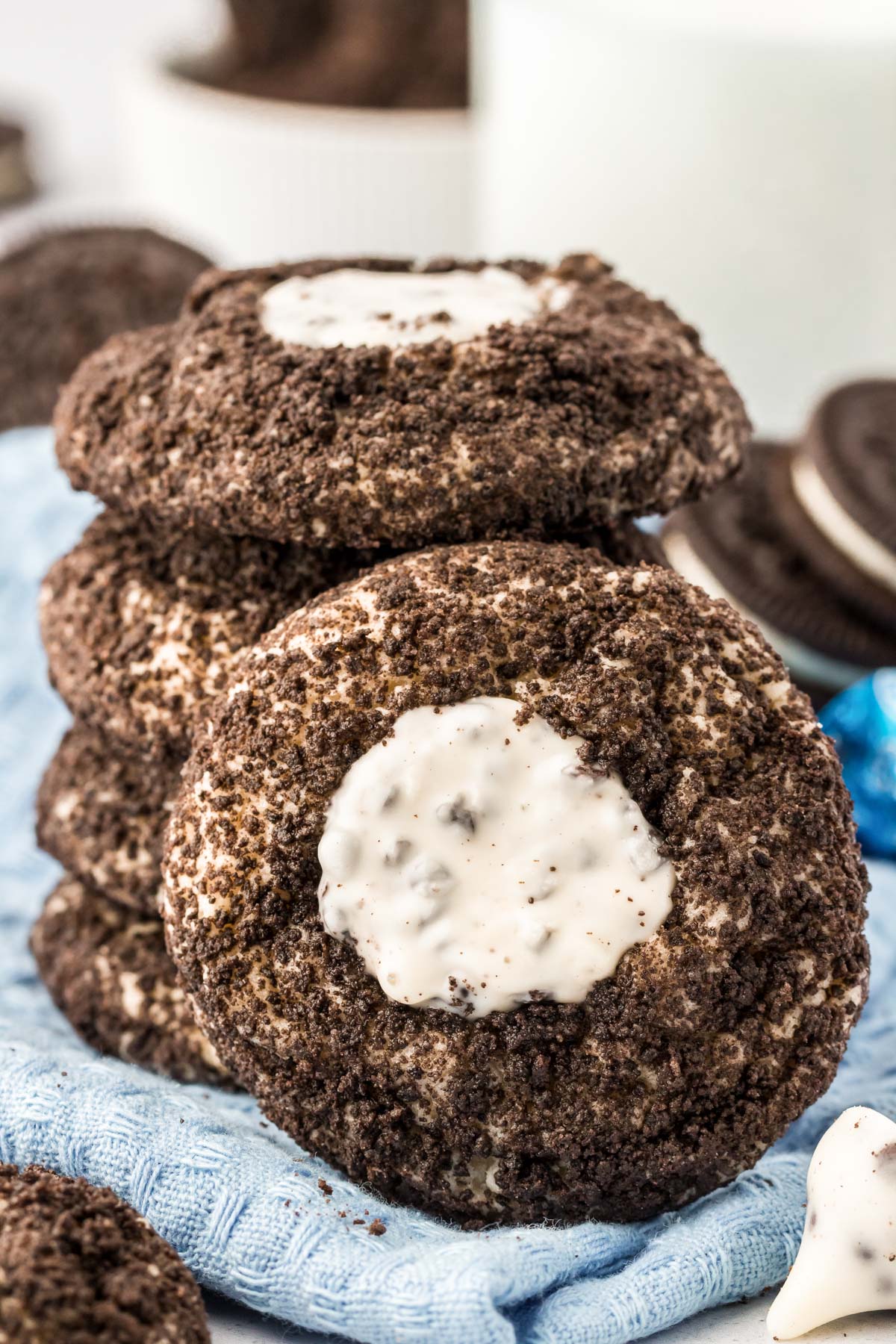 A stack of Oreo thumbprint cookies with one leaning against it.