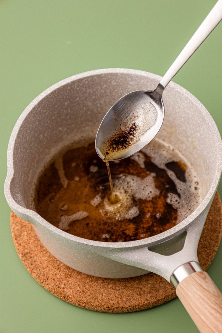 A spoon spooning brown butter out of a pot.