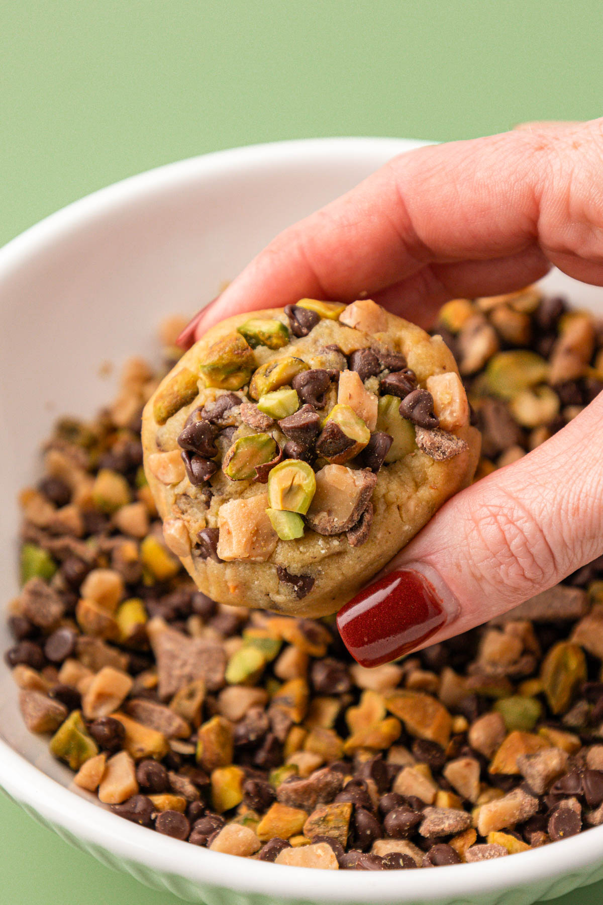 Pistachio Toffee Chocolate Chip Cookies being coated in more.