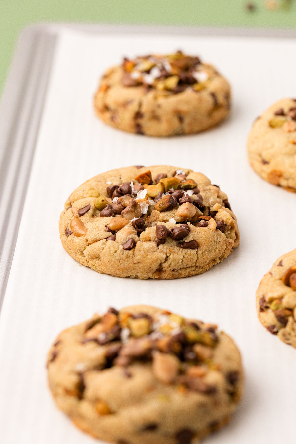 Pistachio Toffee and Chocolate Chip Cookies on a white parchment paper.