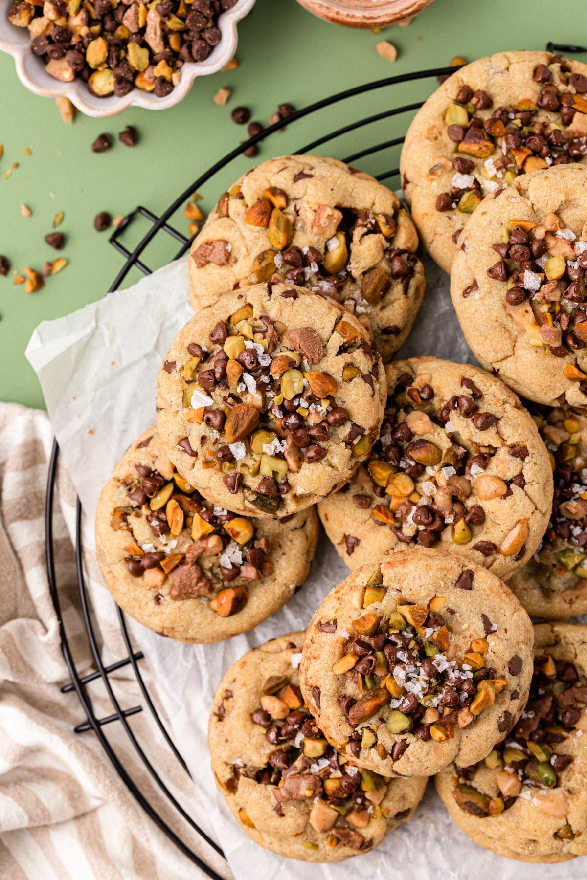 Overhead photo of toffee chocolate chip and pistachio cookies on a black wire rack.