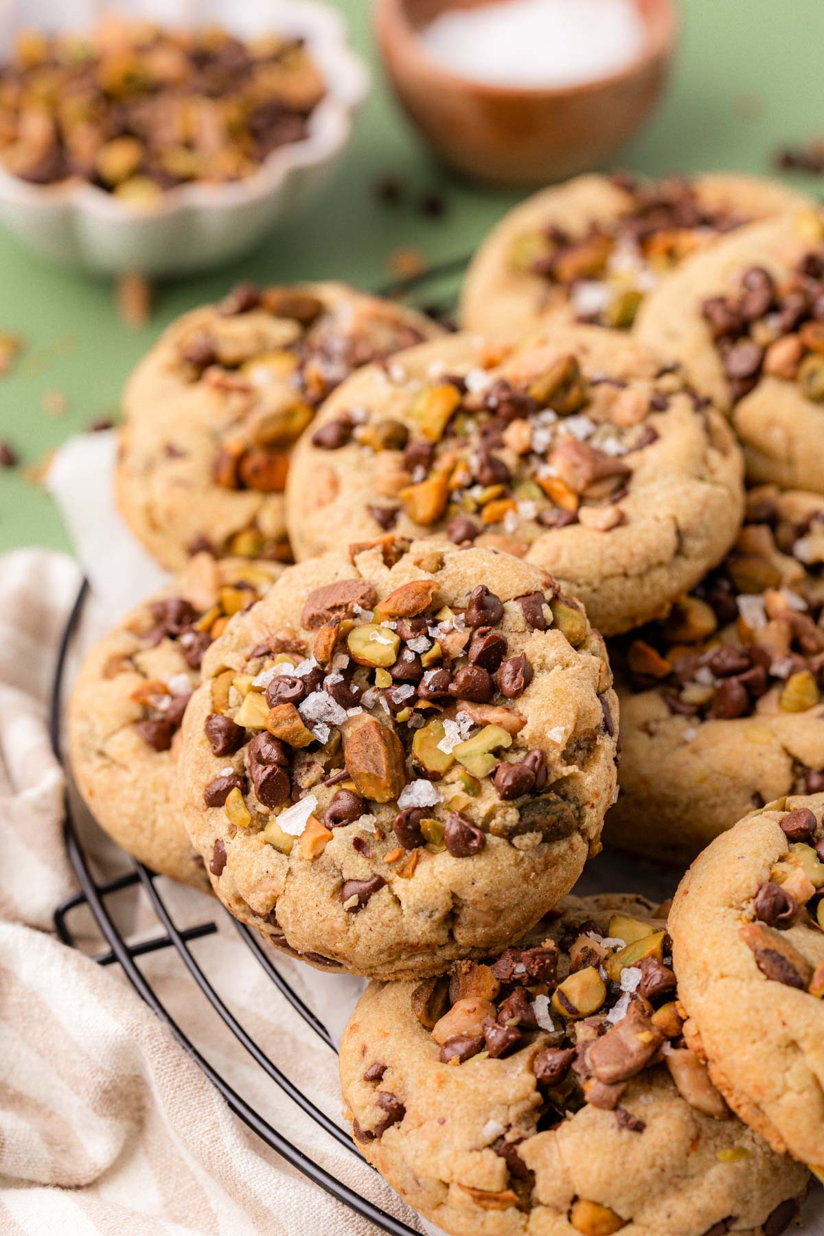 Pistachio toffee chocolate chip cookies on a wire rack.