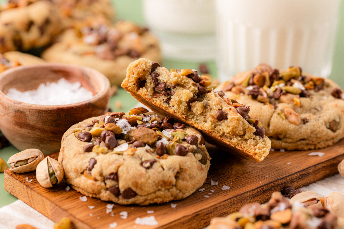 A wooden board with chocolate chip pistachio cookies.
