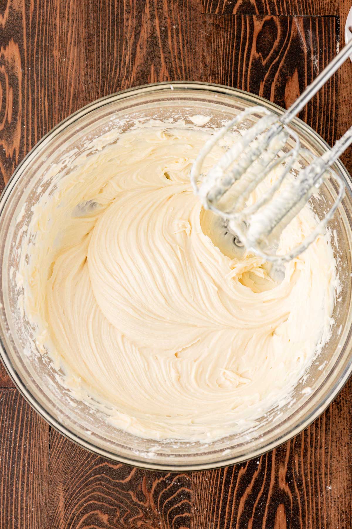 Cream cheese and powdered sugar beaten together in a glass mixing bowl.