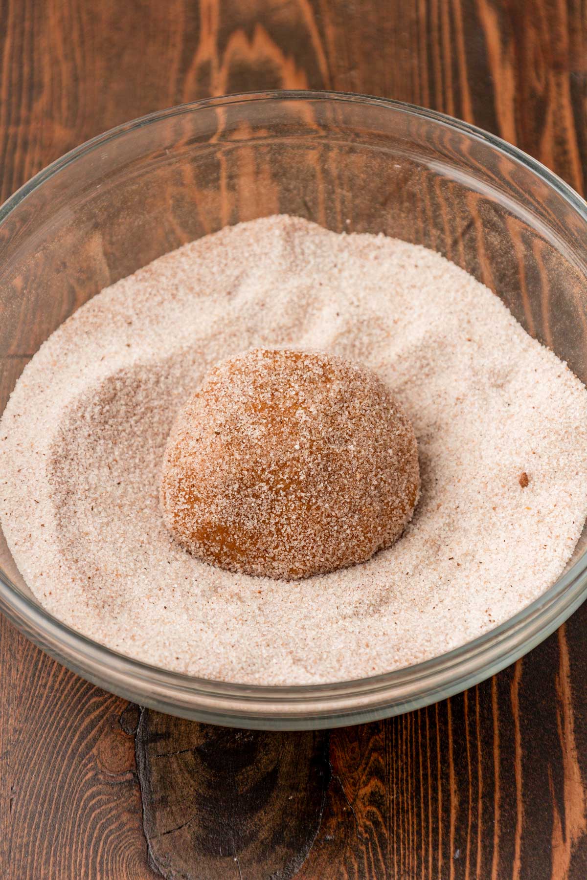 Pumpkin cookie being rolled in a sugar and pumpkin spice mix.