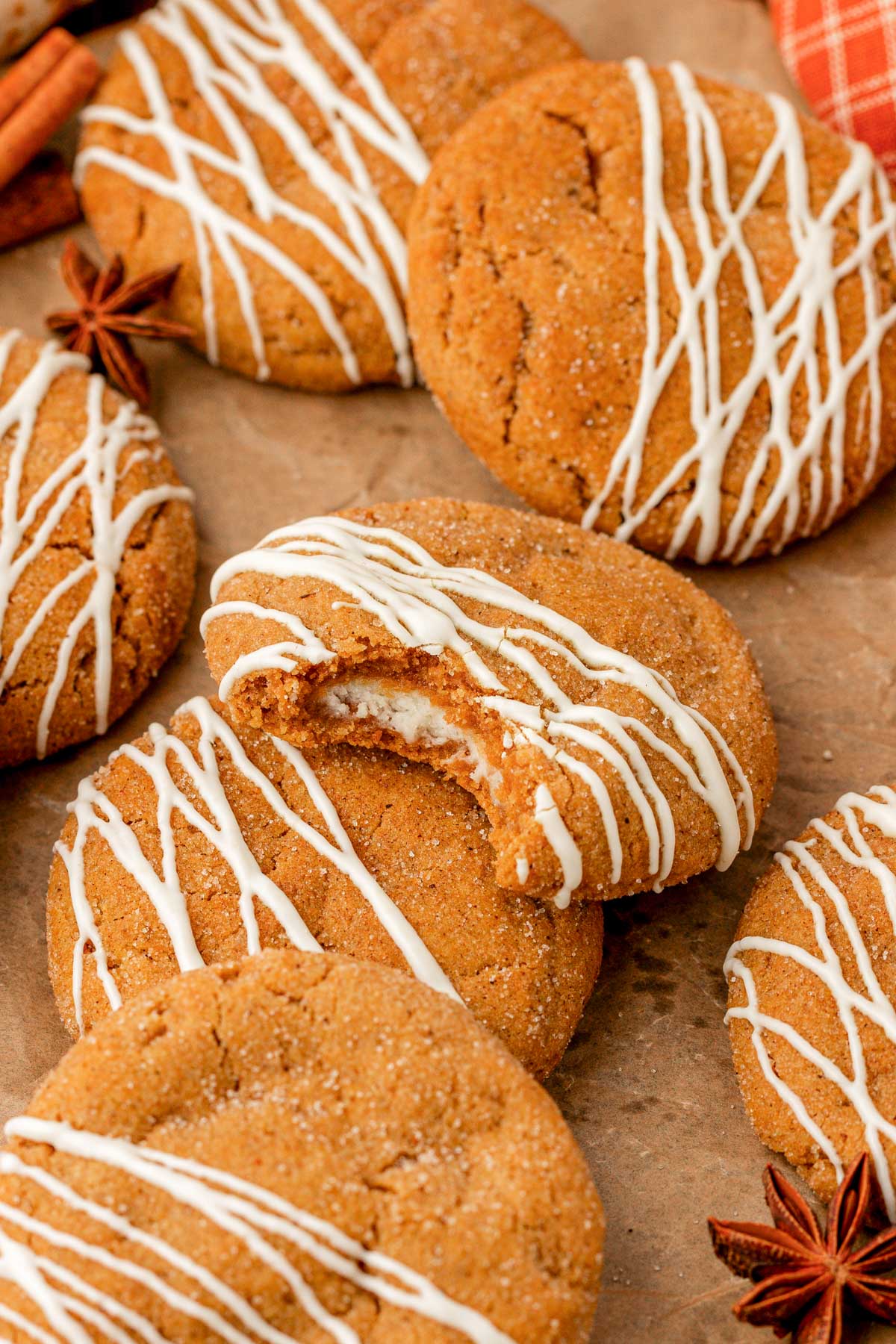 Pumpkin cheesecake cookies drizzled in white chocolate on parchment paper.