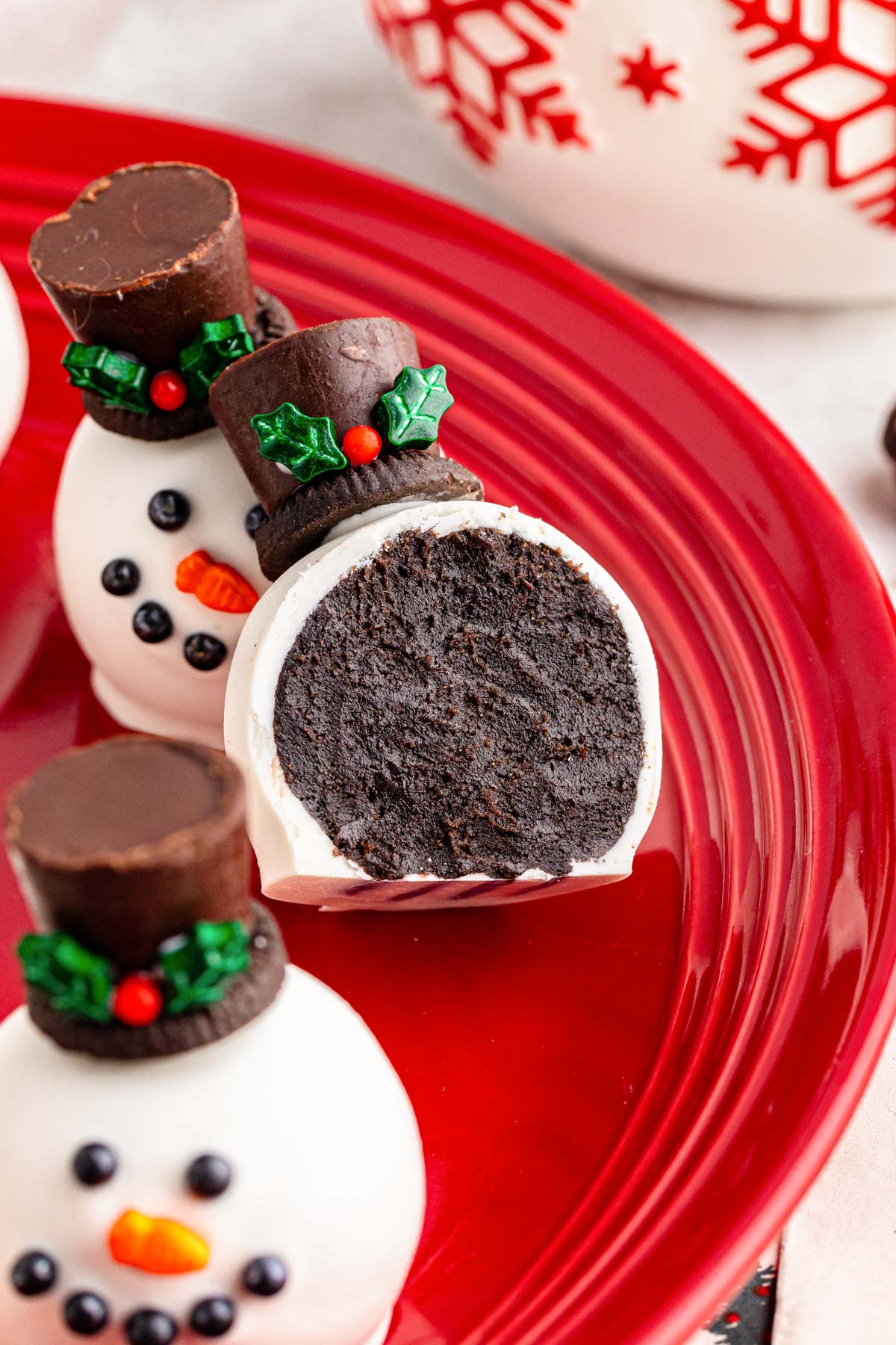 Close up of a snowman oreo ball on a red plate that's been bitten into.