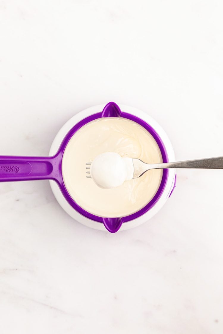 An Oreo Ball being dipped in white chocolate.