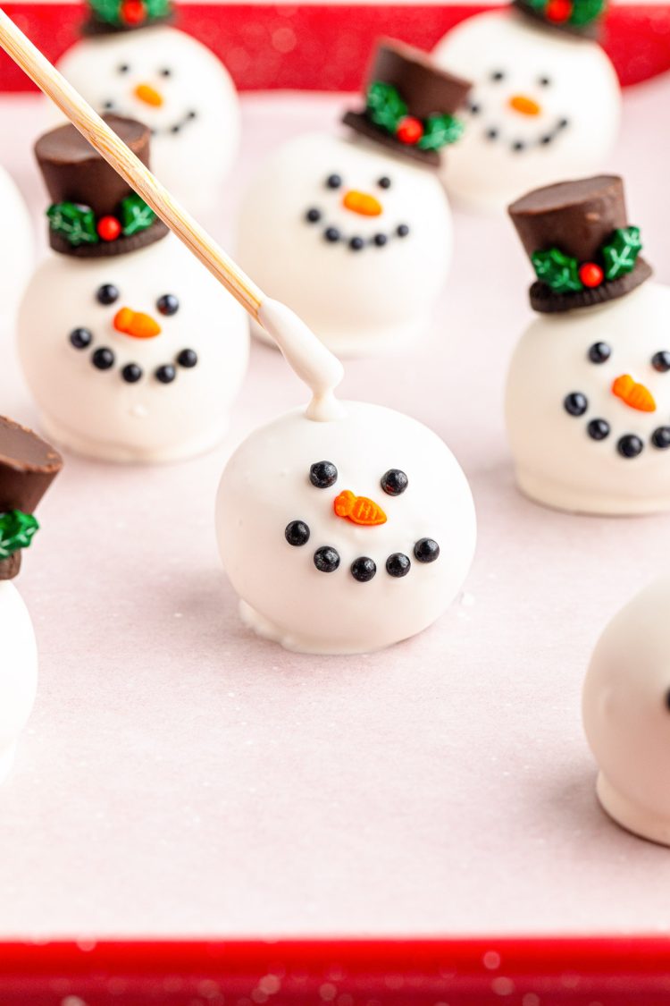 A white chocolate covered oreo ball with a snowman face.