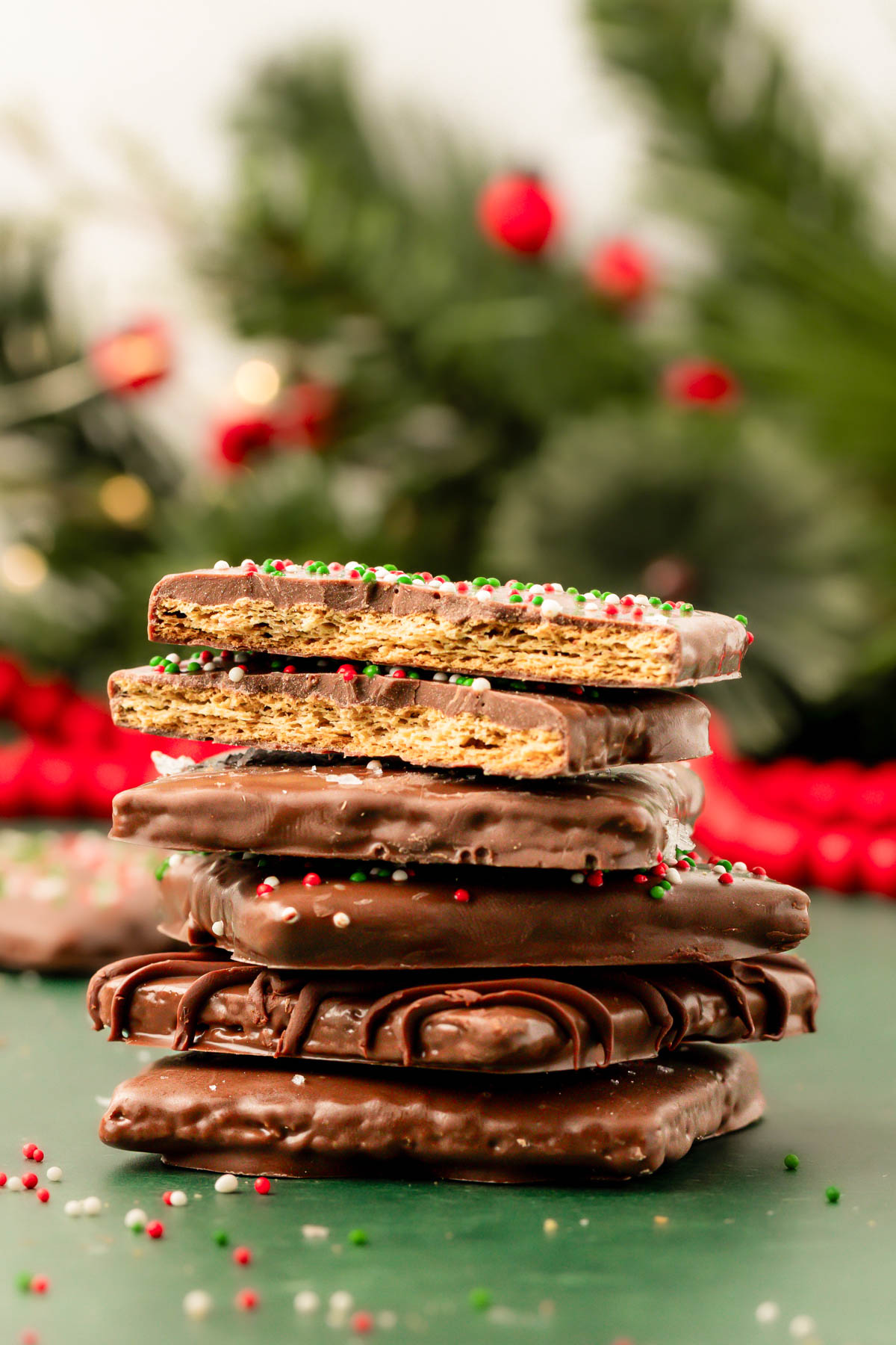 A stack of chocolate  coated graham crackers on a green surface.