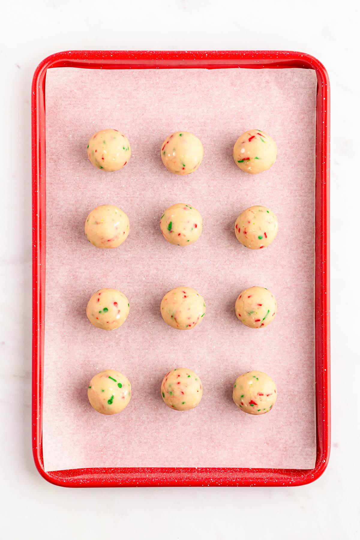 Sugar cookie truffle balls on a parchment lined baking sheet.