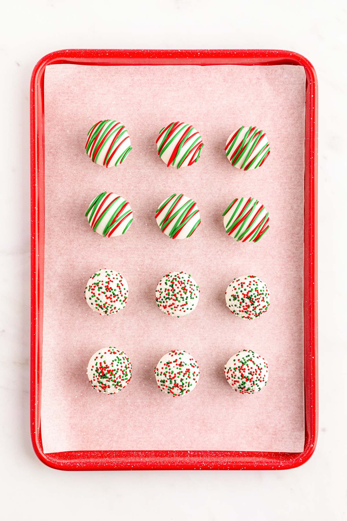 Cookie truffles decorated for Christmas on a baking sheet.