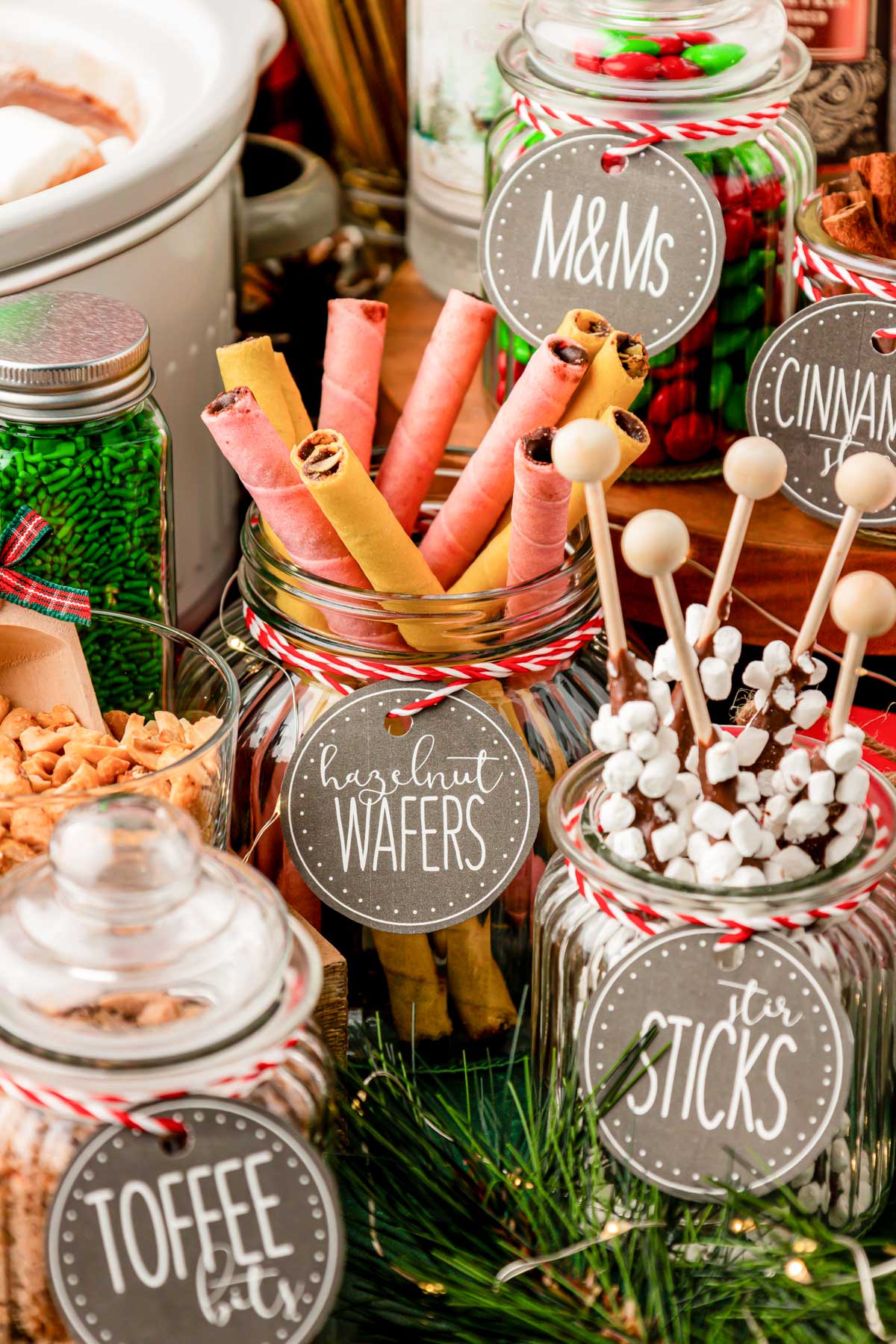 Hot chocolate bar toppings in jars on a table.