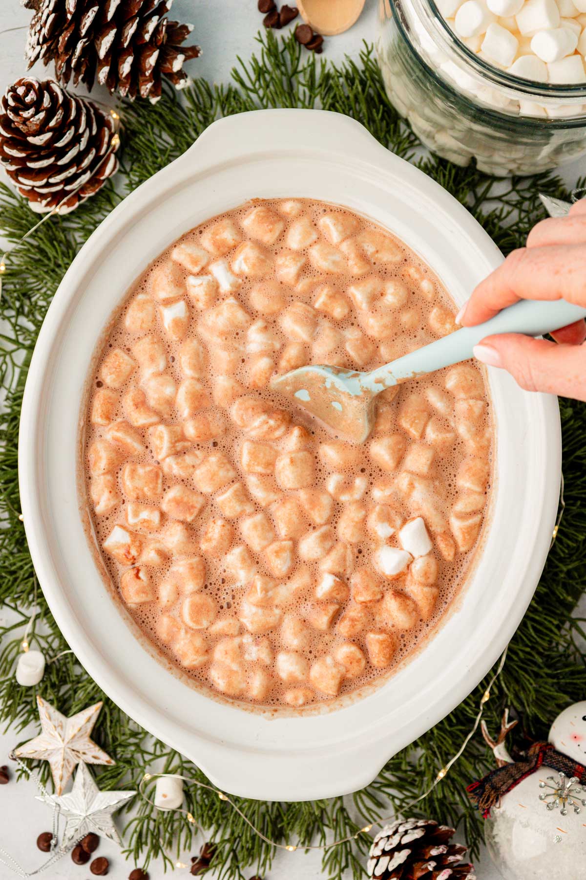 Marshmallows covereung the surface of a slow cooker filled with hot chocolate.