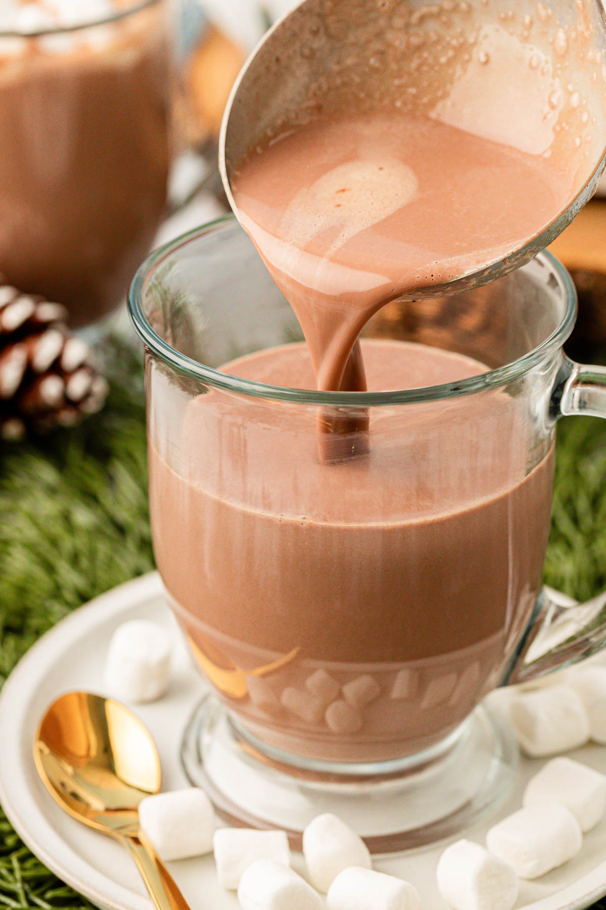 Hot chocolate being ladled into a glass mug.