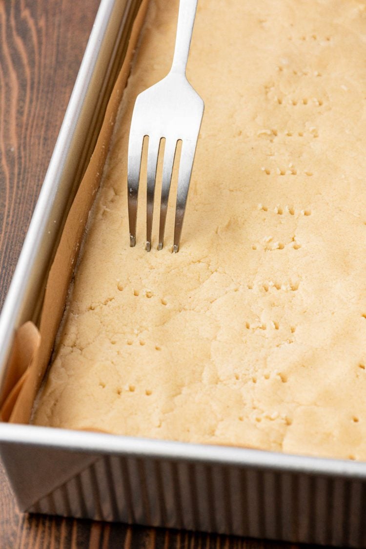 A fork poking shortbread dough all over. 