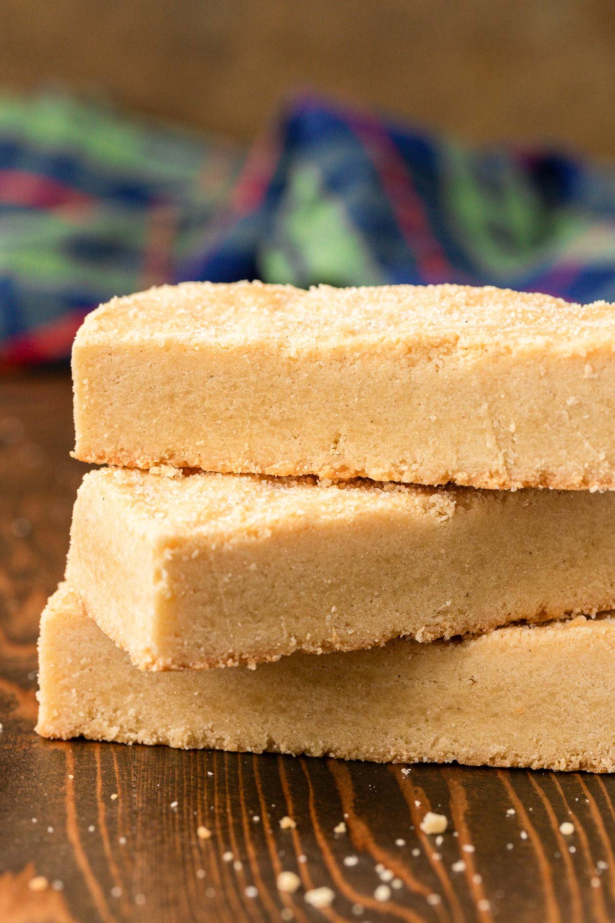 A stack of three shortbread cookie bars on a wooden table.