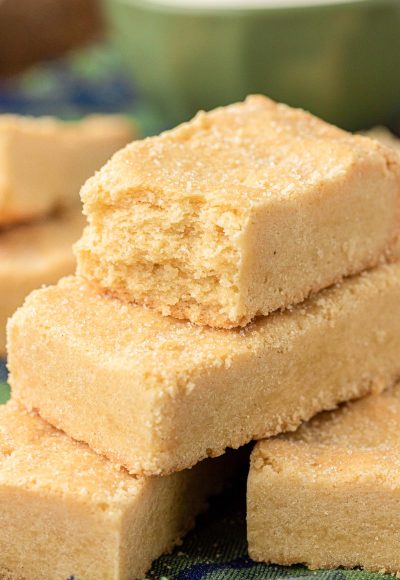 Close up of shortbread cookie bars stacked on a wooden table.