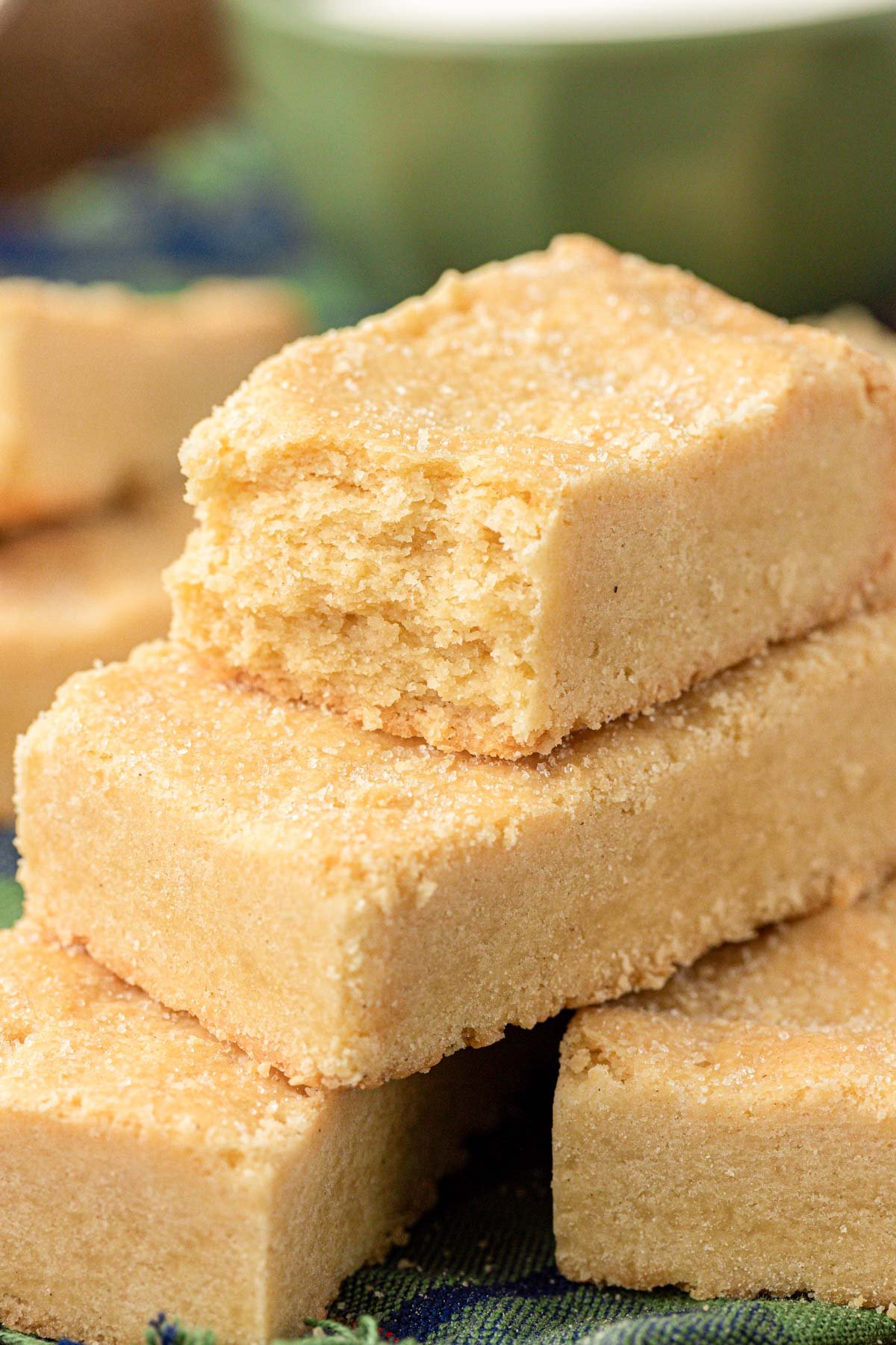 Close up of shortbread cookie bars stacked on a wooden table.