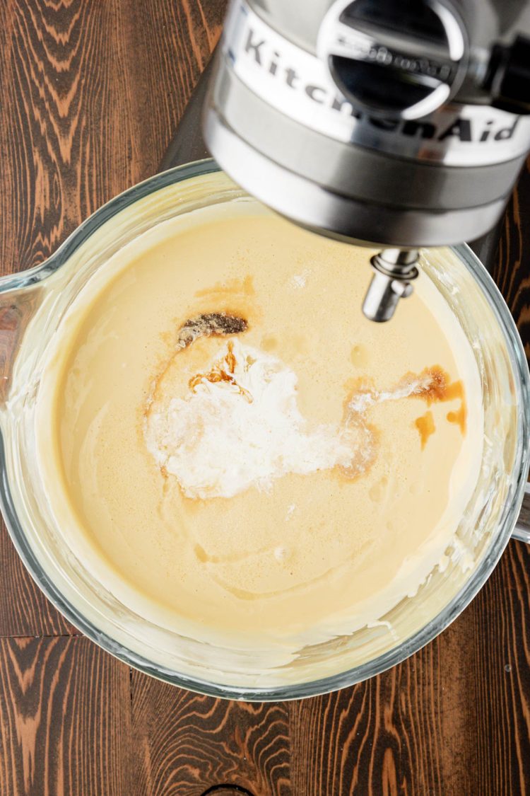 Ingredients being added to a glass mixing bowl to make cheesecake.