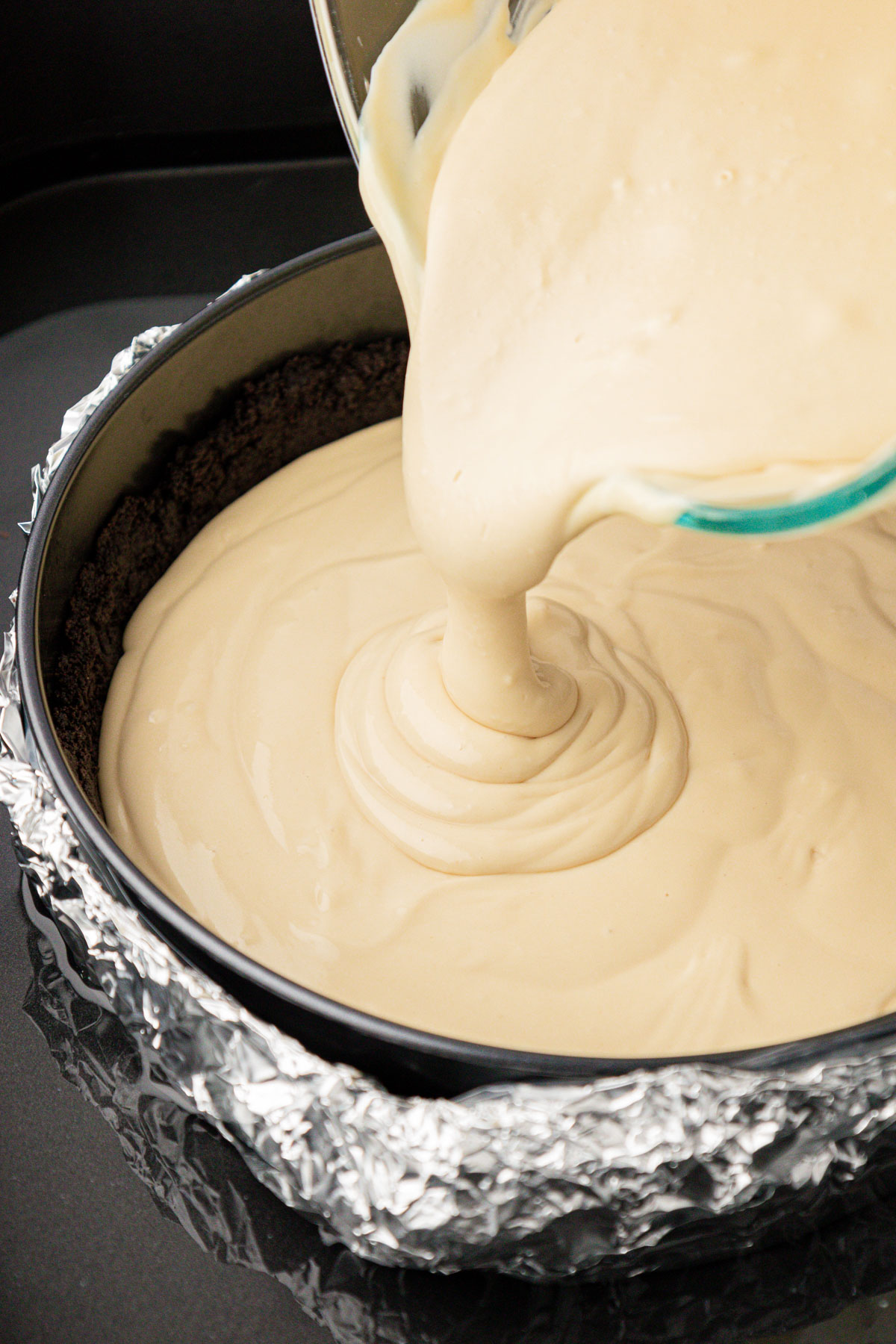 Coffee cheesecake filling being poured into a springform pan.