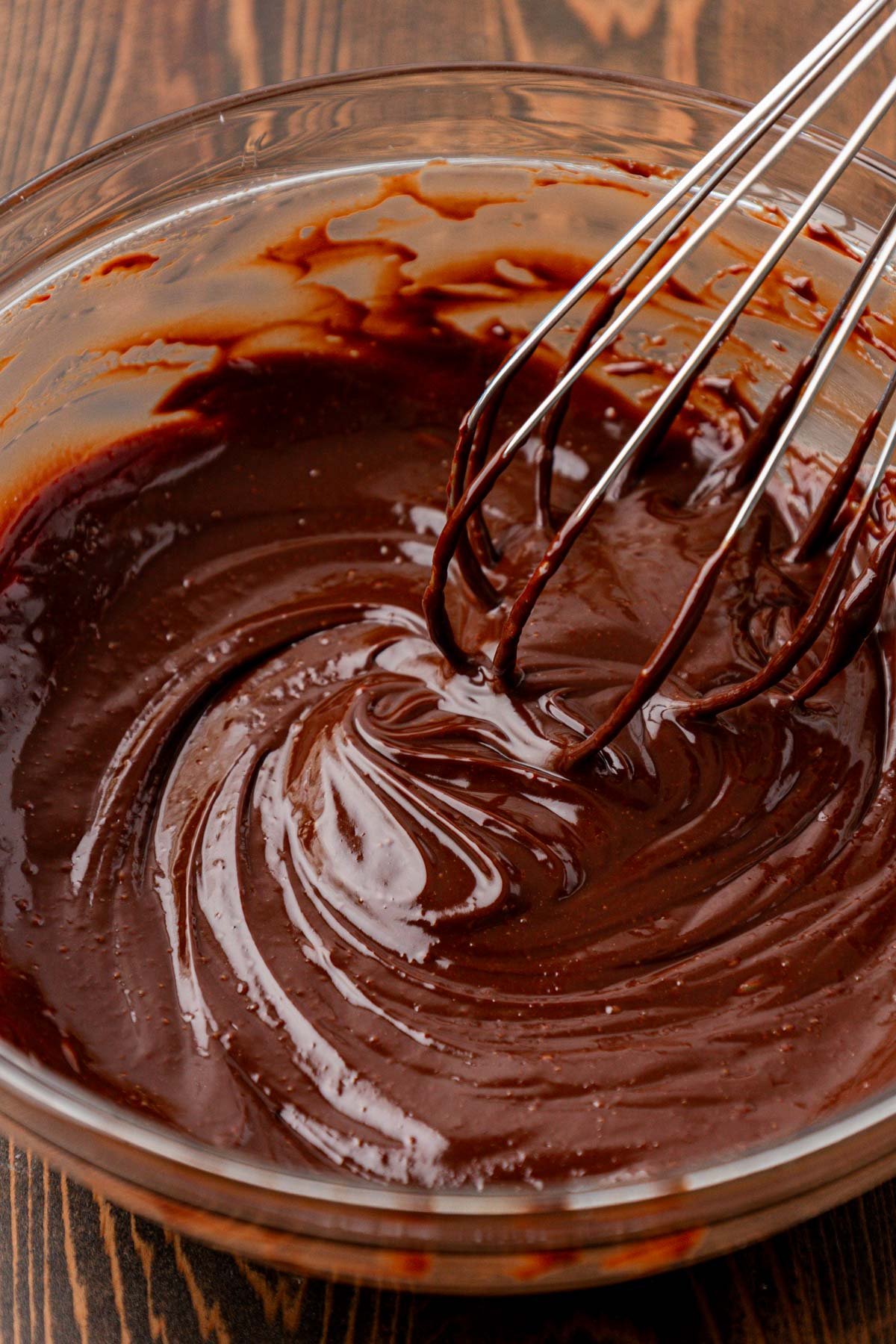 Chocolate ganache being whisked in a glass bowl.