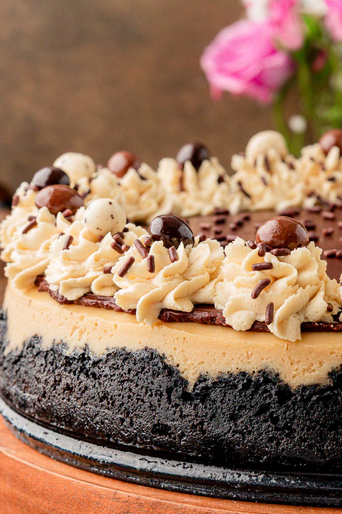 Close up of a coffee cheesecake on a wooden cake stand.