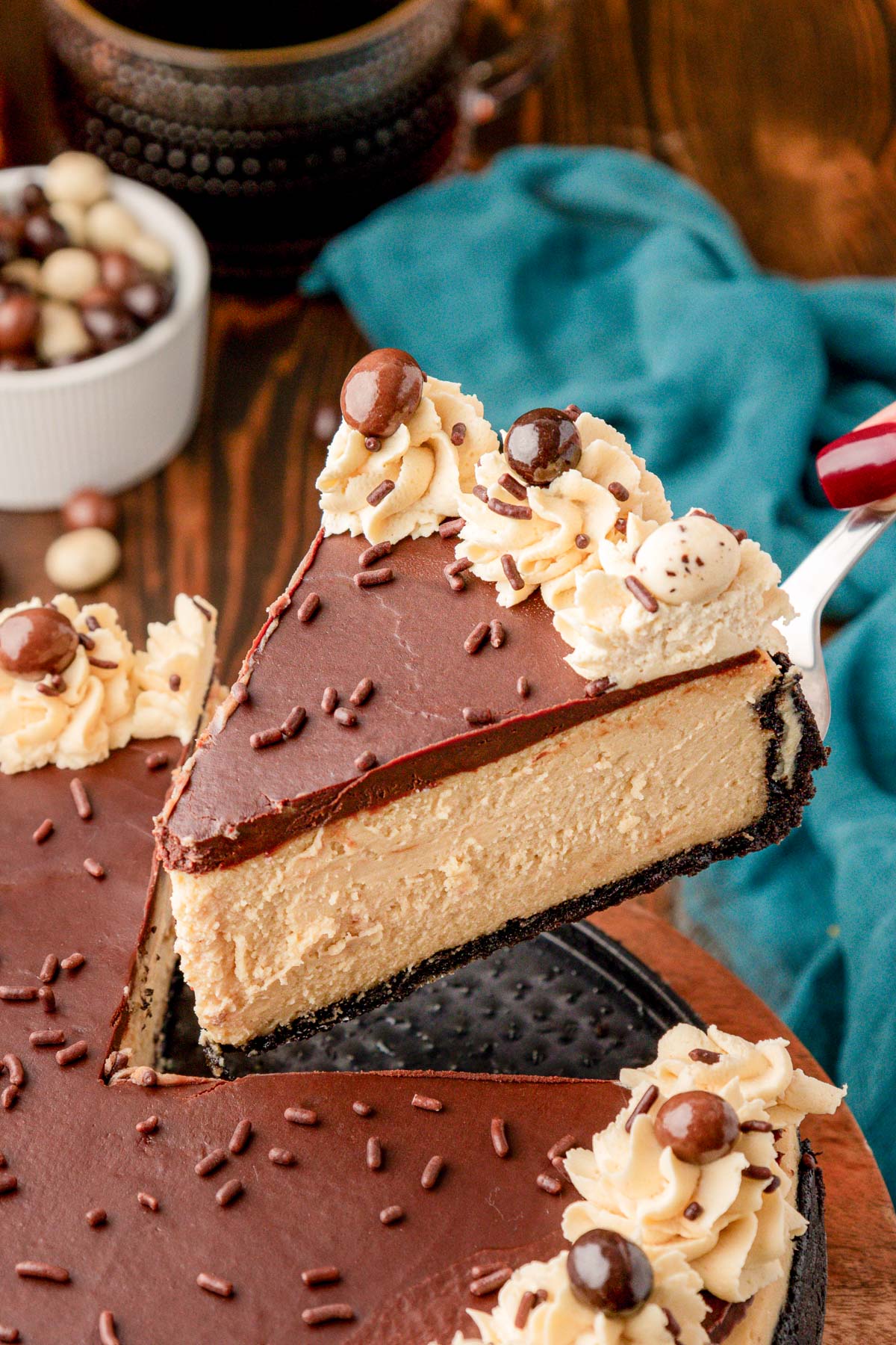 A slice of chocolate topped coffee cheesecake being lifted away from the rest of it.