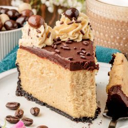 A slice of coffee cheesecake on a white plate with a bite missing.