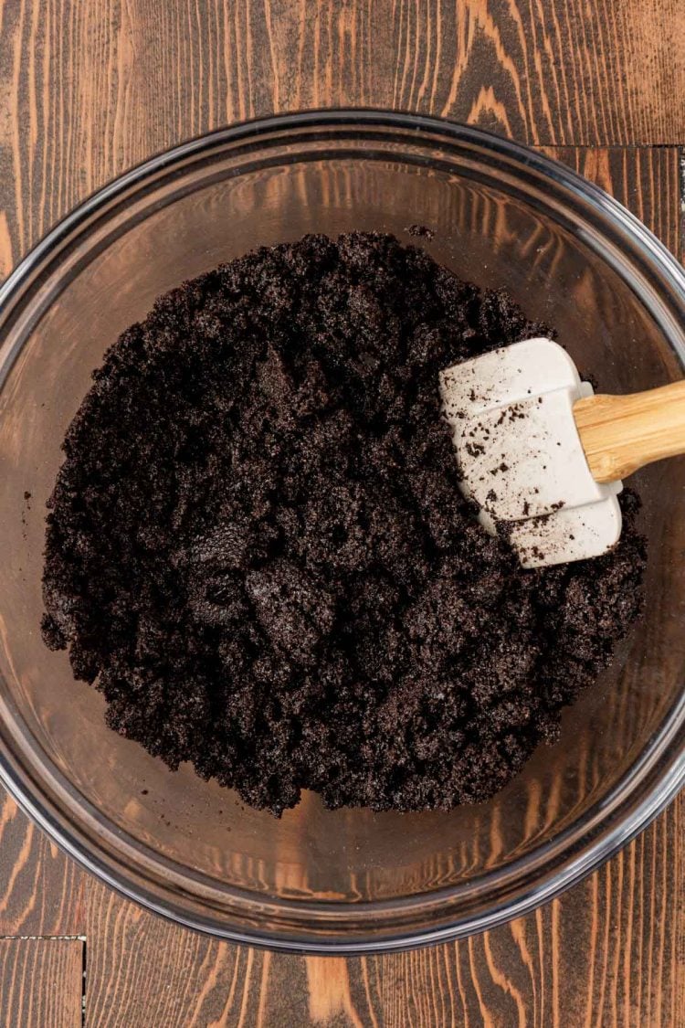 Oreo crust mixture being mixed in a glass bowl.