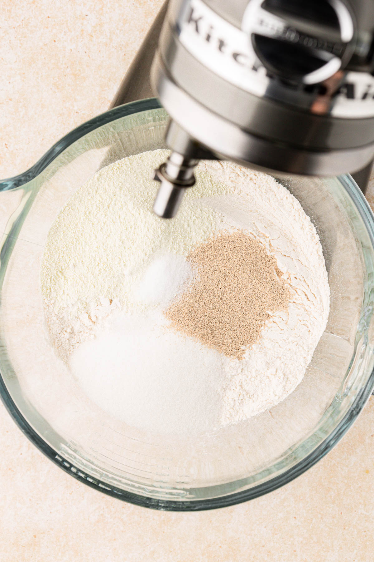 Dry ingredients to make cinnamon rolls in a glass mixing bowl.