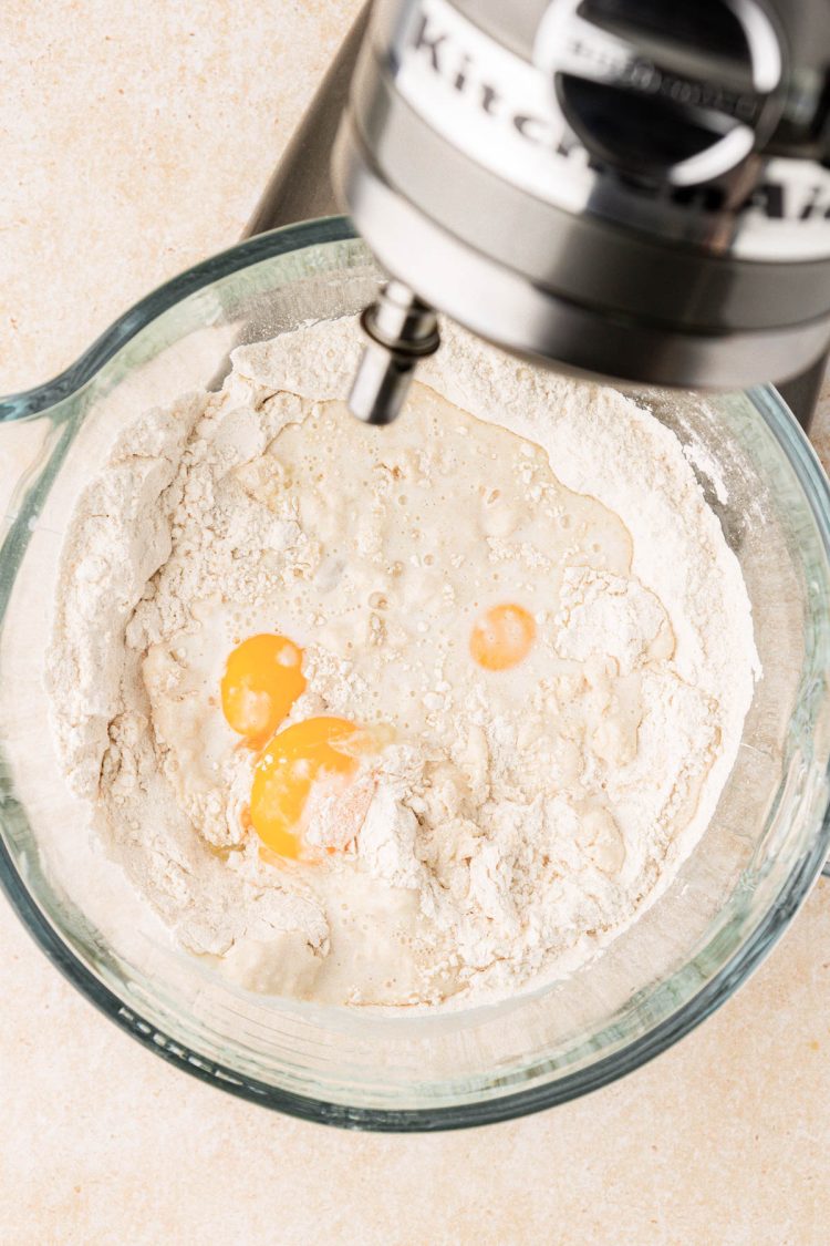 Eggs being added to dry ingredients in a mixing bowl.