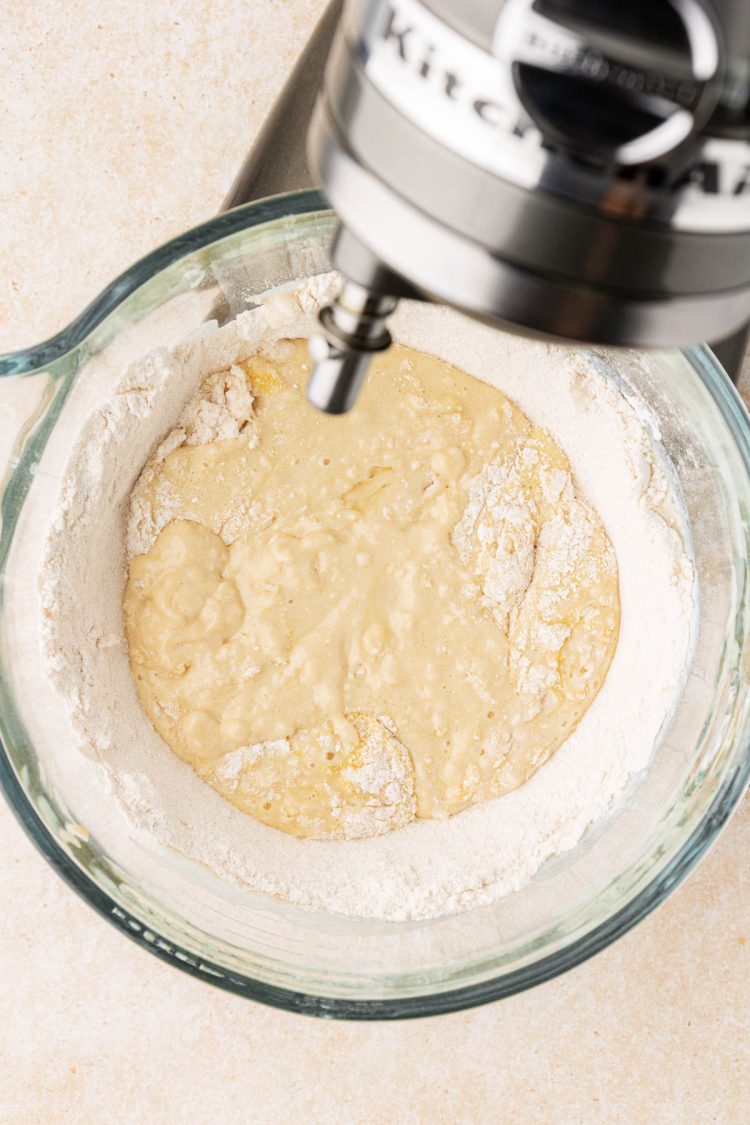 Cinnamon roll dough being made in a glass stand mixer bowl.