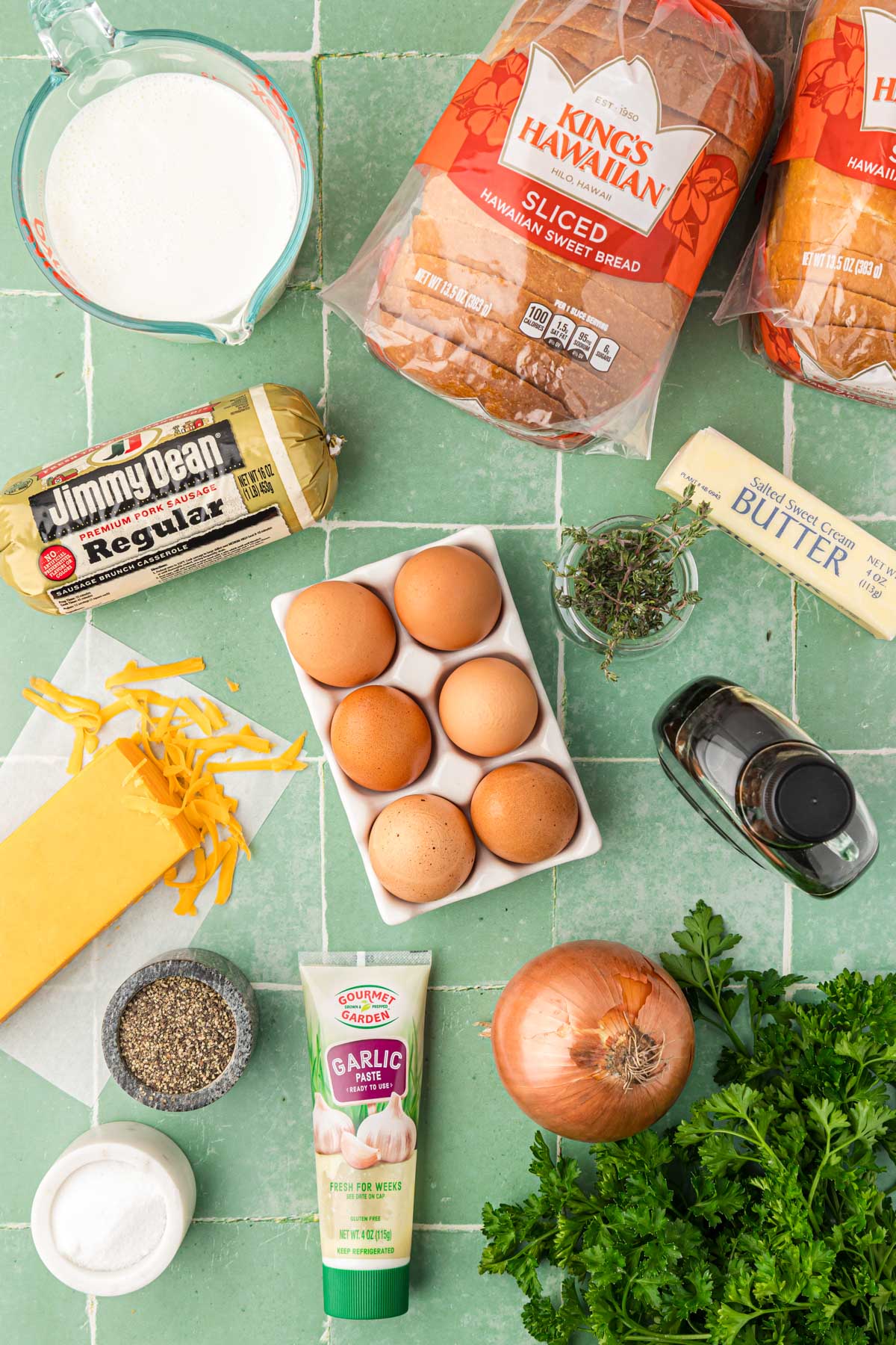 Overhead photo of ingredients to make a breakfast strata on a green tile surface.