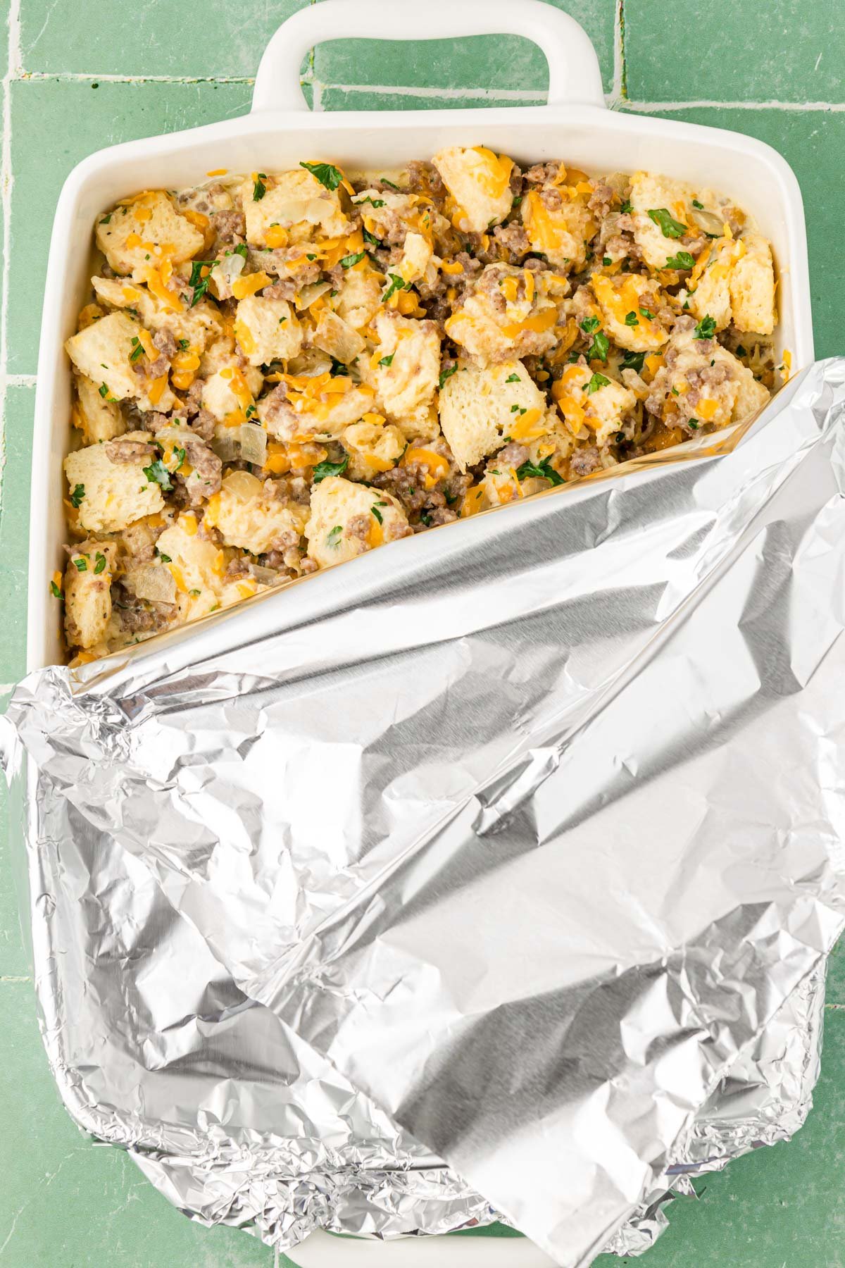 Aluminum foil covering a baking pan filled with breakfast casserole ingredients to soak overnight.