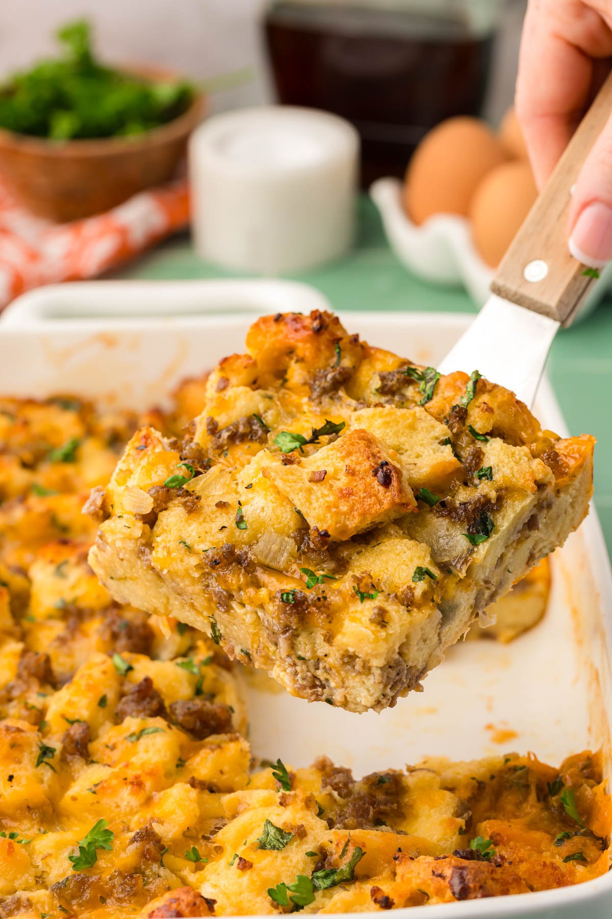 A slice of breakfast strata on a spatula being lifted from the pan.