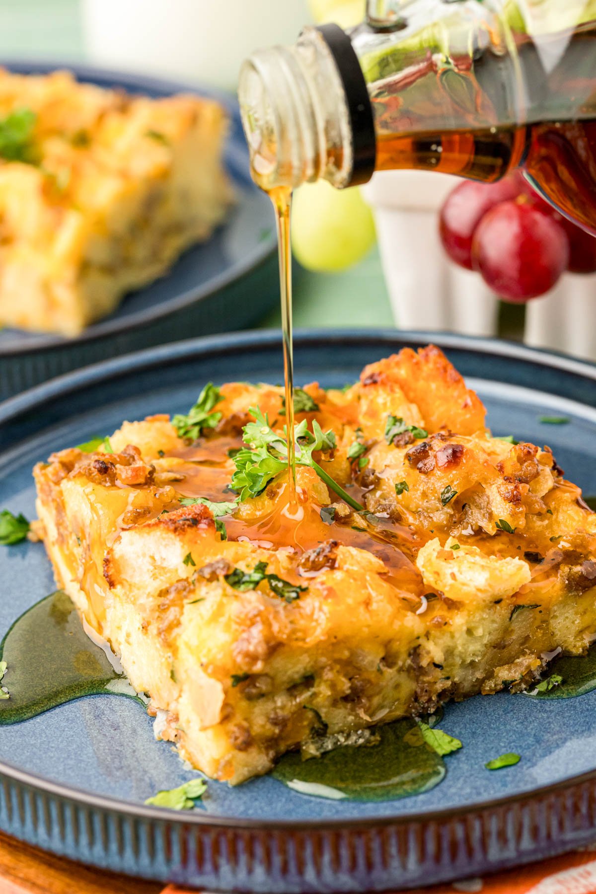 Syrup being poured over a slice of breakfast strata.