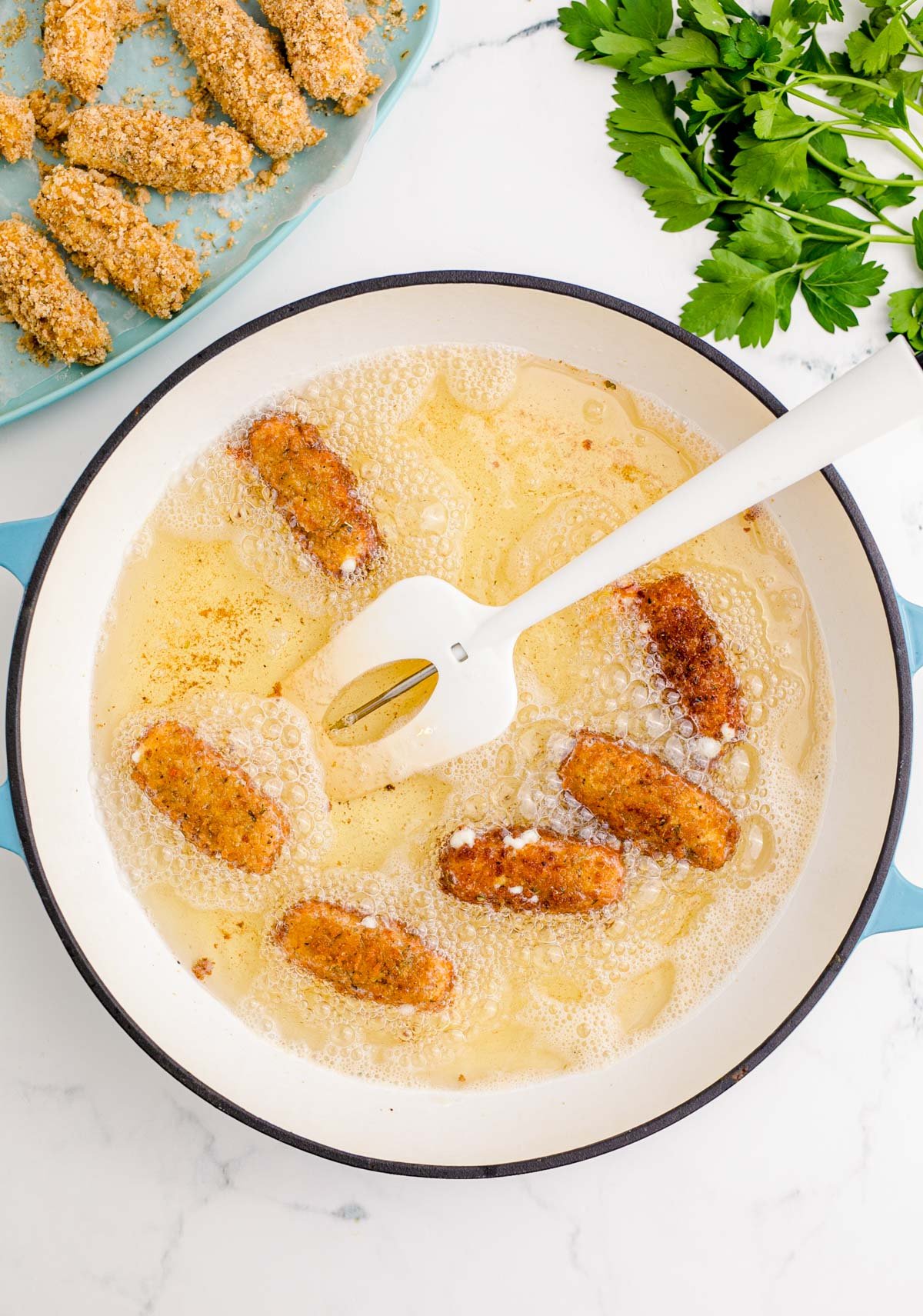 Mozzarella Sticks being fried in a dutch oven.