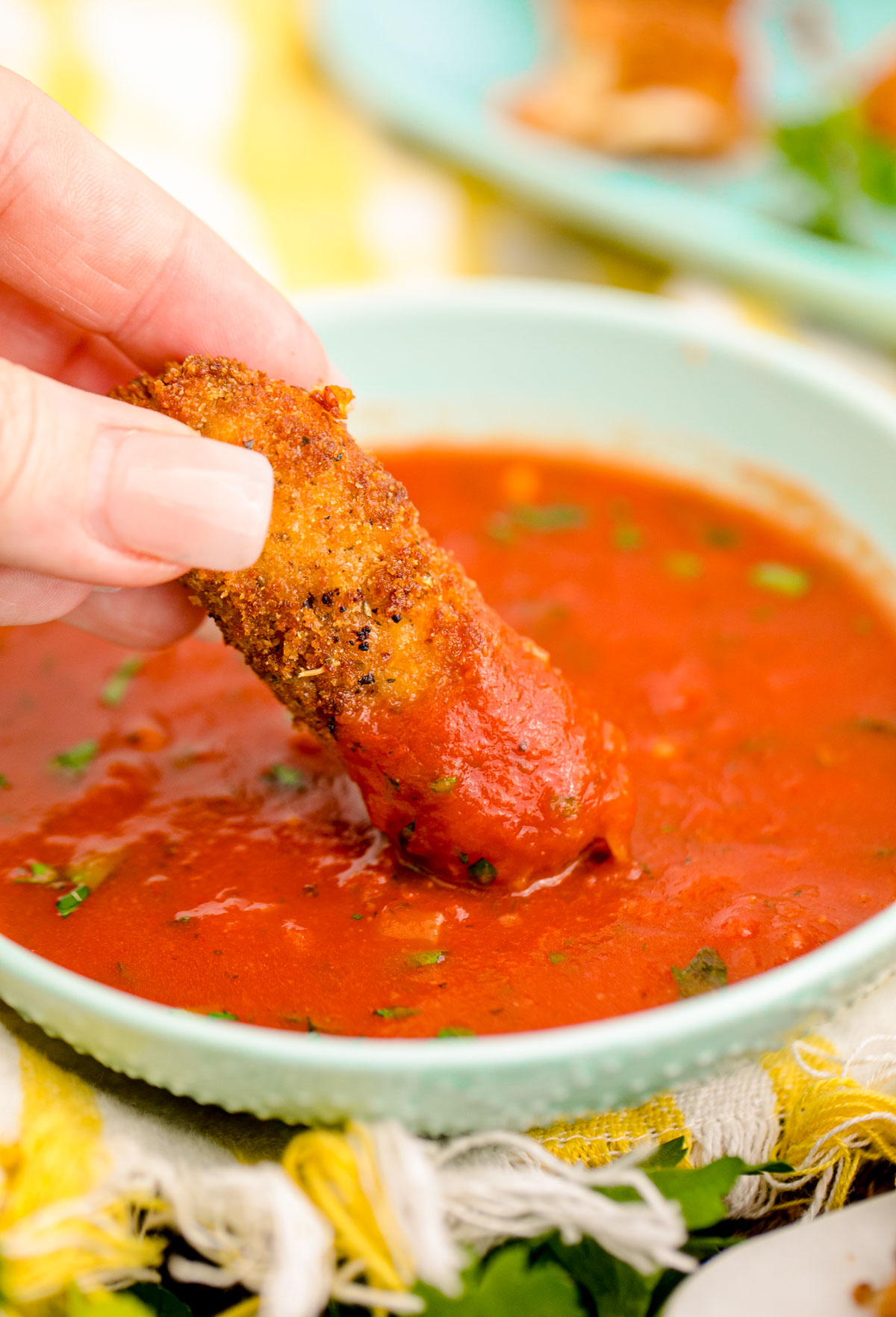 Mozzarella sticks being dipped in marinara sauce.