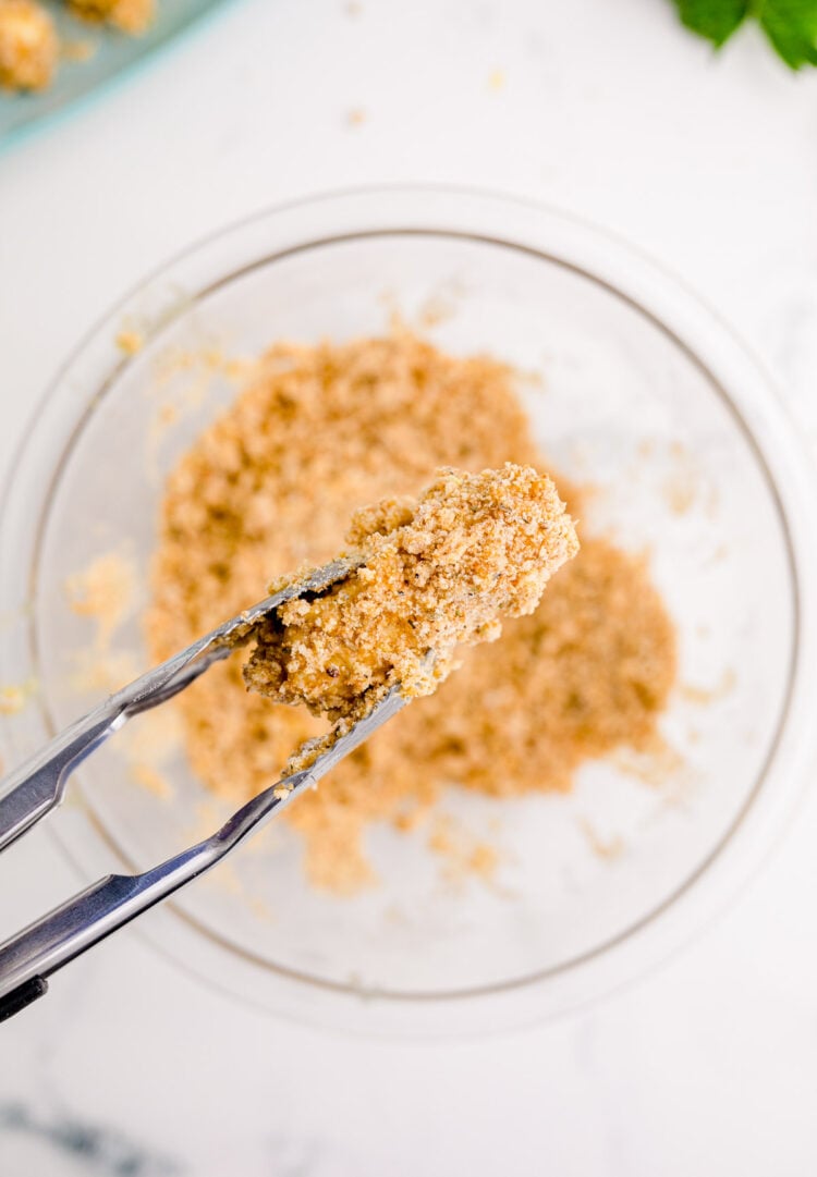 A mozzarella stick coated in bread crumbs ready to be fried.