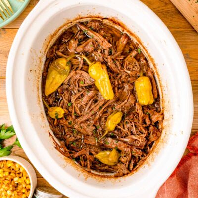 Overhead photo of a white crockpot filled with Mississippi Pot Roast.