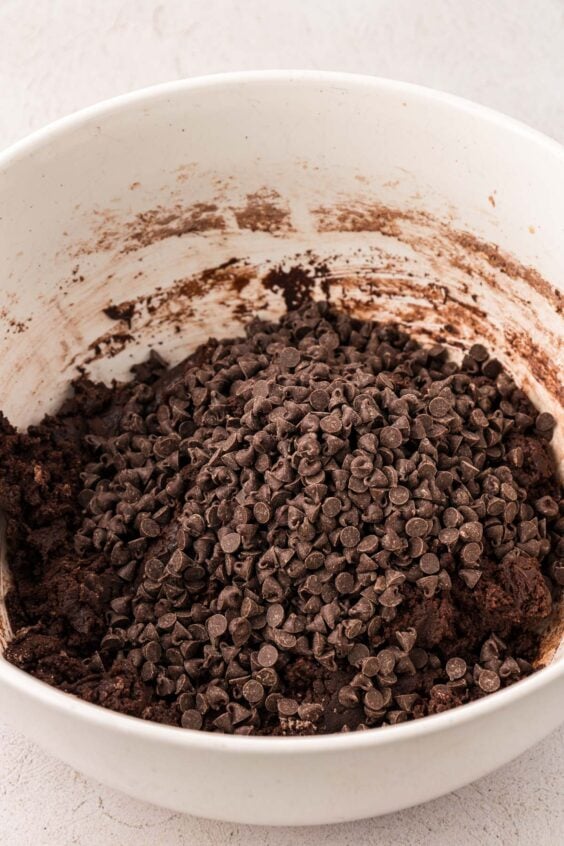 Mini chocolate chips being added to chocolate cookie dough.