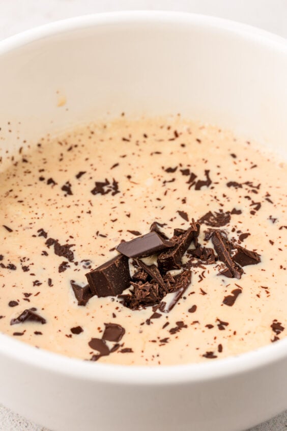 Chopped chocolate and hot cream in a bowl to make ganache.